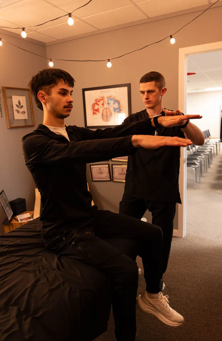 A team member guiding a patient through an arm exercise at Living Well